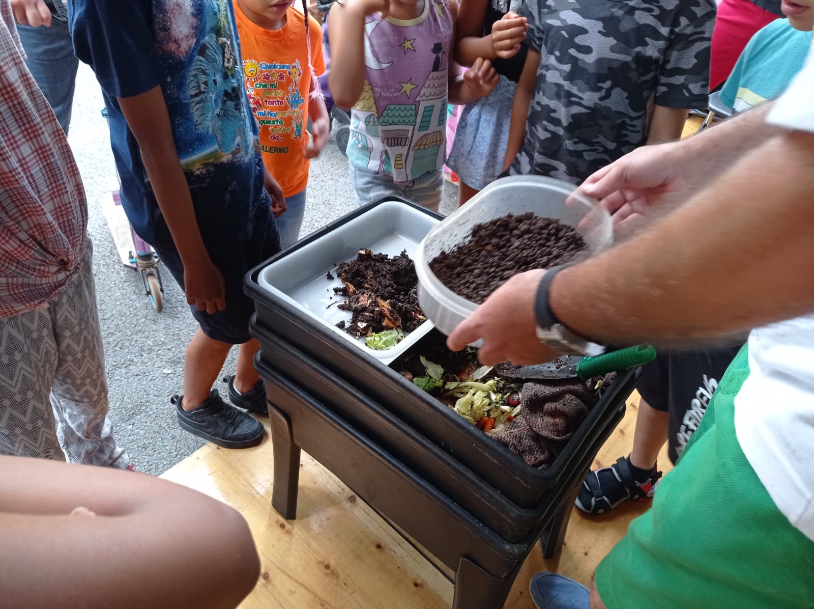 Fotografia de la darrera Festa de la Ciència, amb públic de diferents edats observant diferents estats de descomposició de restes orgàniques i una vermicompostadora.