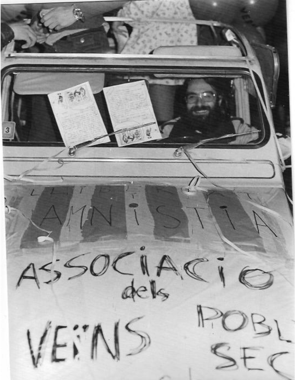 Fotografia dels anys 70 dins d'un cotxe tot pintat amb les paraules AMNISTIA i Associació dels veins del Poble-sec