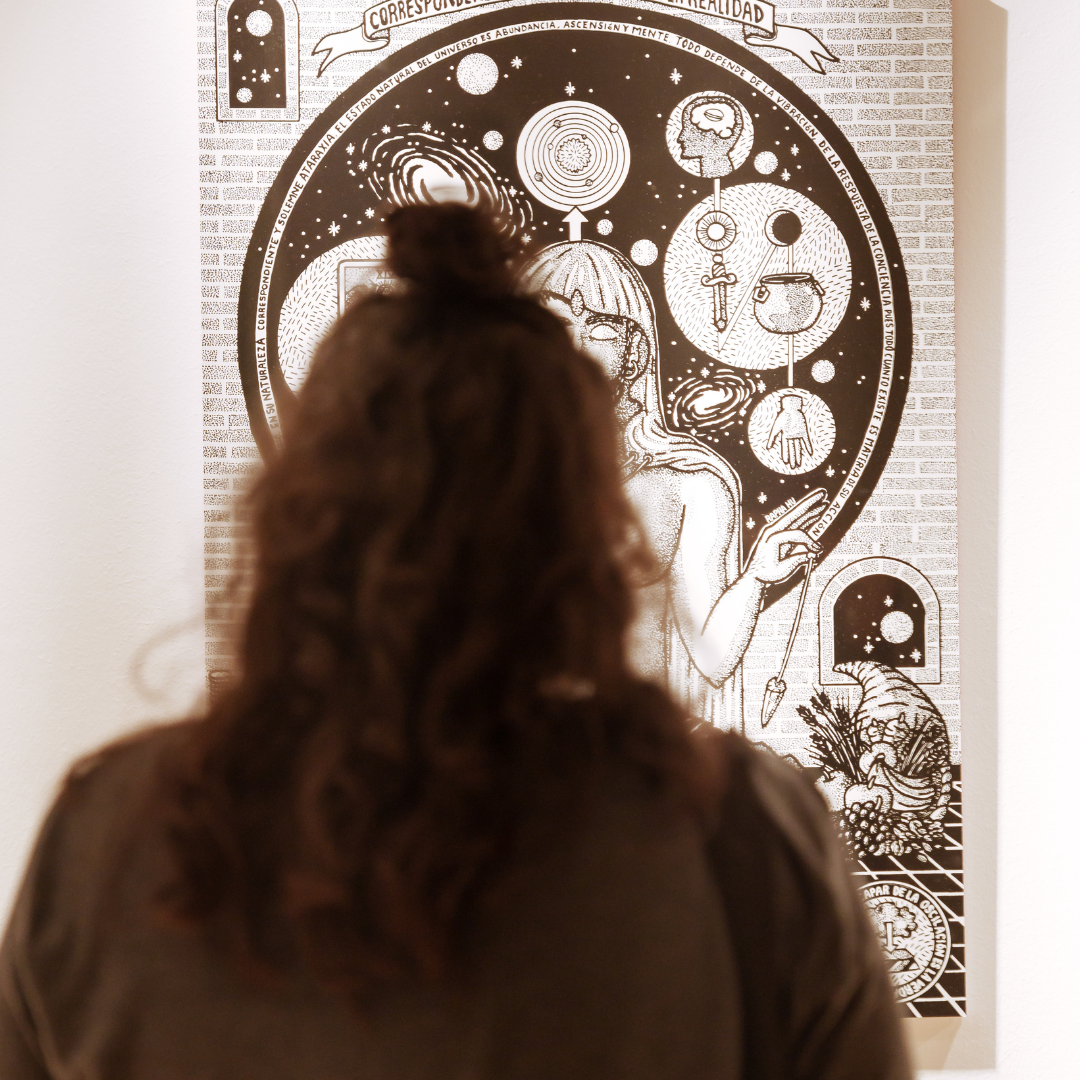 Una persona mira una de les obres de l'exposició "Encanteris i dissidències"