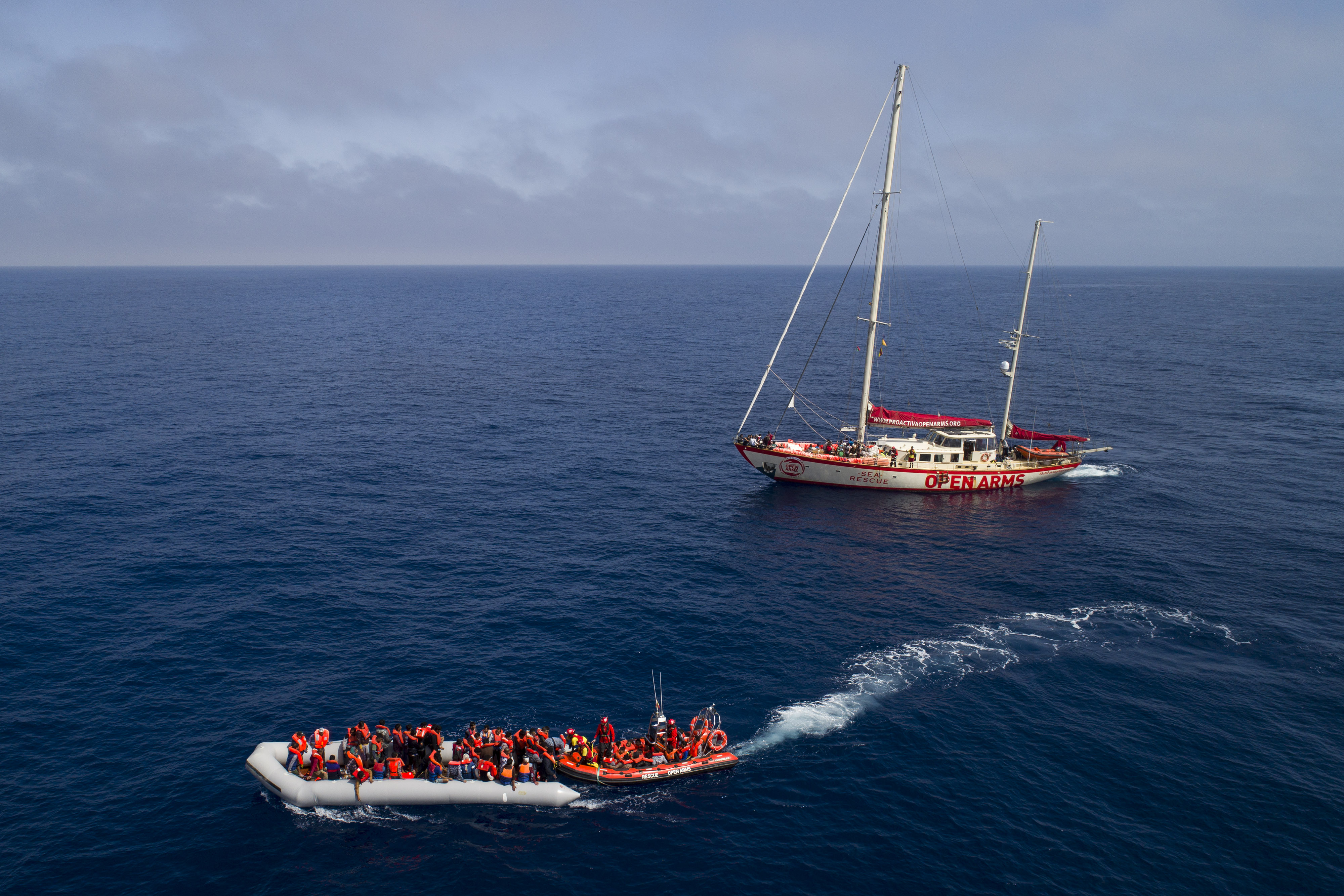 Fotografia d'una embarcació i el vaixell d'Open Arms al Mediterrani