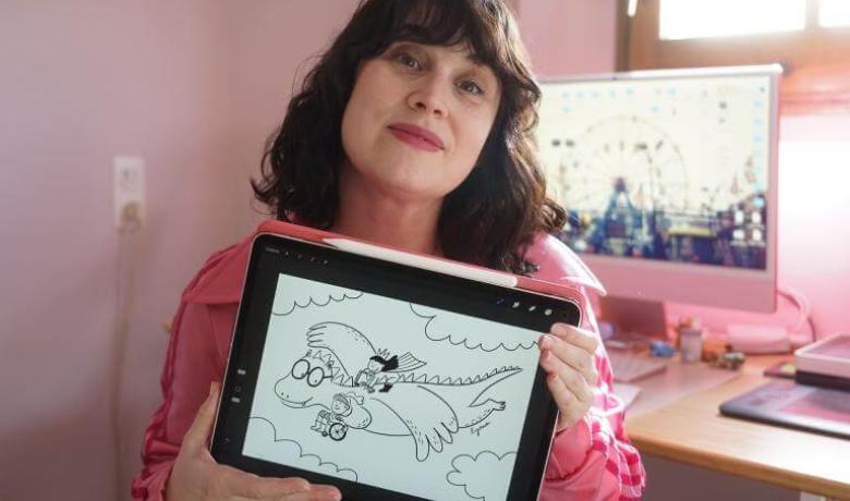 Lyona mostra el dibuix que ha dissenyat per al Sant Jordi Divers 25. A la il·lustració, Sant Jordi utilitza cadira de rodes i es troba acompanyat per un drac amigable i per la princesa.