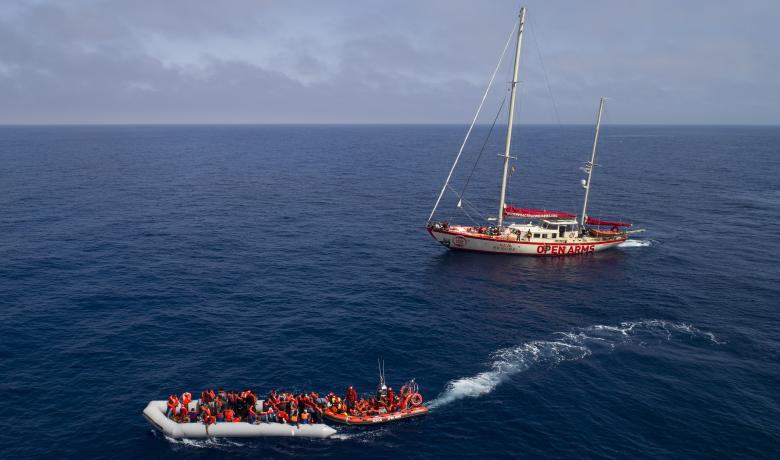 Fotografia d'una embarcació i el vaixell d'Open Arms al Mediterrani