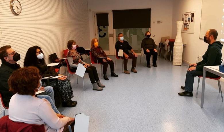 Un grup de gent amb mascaretes i els ulls tancats seuen en rotllana, aparentment meditant