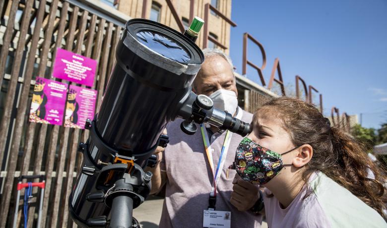 Una noia observa per un telescopi de l'Associació Aster Barcelona