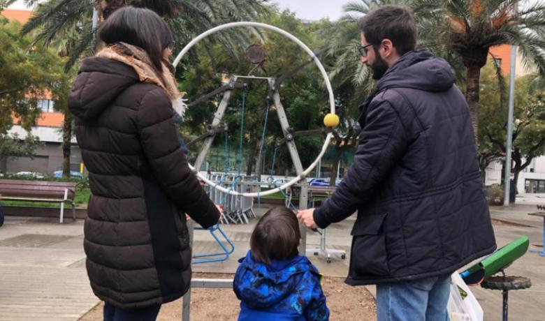 Un infant juga, amb dos adults, a un joc instal·lat al circuit de les joguines