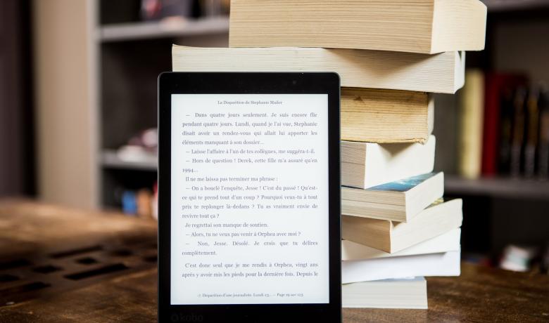 una pila de llibres i un lector d'ebooks
