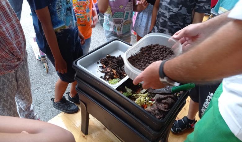 Fotografia de la darrera Festa de la Ciència, amb públic de diferents edats observant diferents estats de descomposició de restes orgàniques i una vermicompostadora.