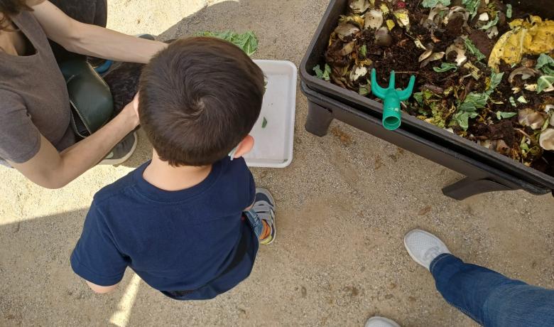 Imatge d'una criatura d'esquenes durant l'activitat amb una vermicompostadora.