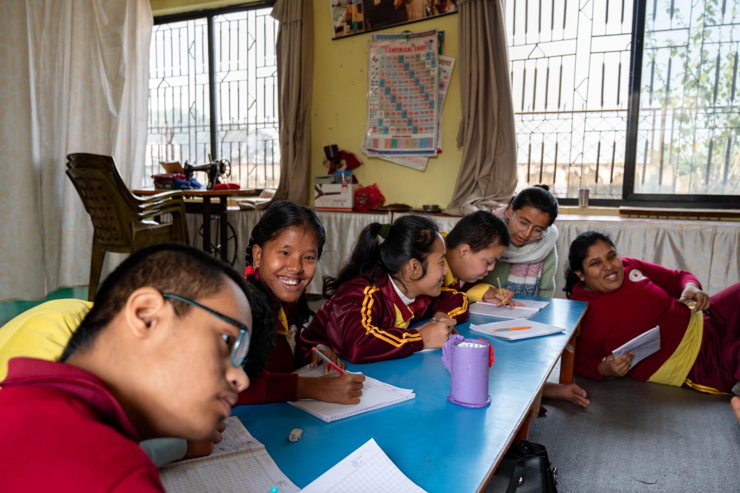Infants i joves amb discapacitat intel·lectual participen en una activitat educativa a l’aula, acompanyats per una mestra. La fotografia va ser presa a Hetauda, a l’Asha School, una escola de l’entitat Familia de Hetauda.